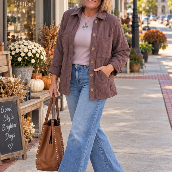 Woman wearing a mauve-brown quilted button-front jacket with a lavender top, wide-leg jeans, and a brown tote outside Saffron and Sage Boutique