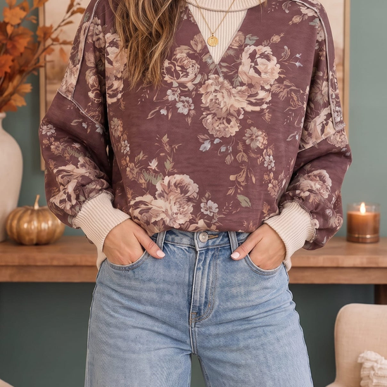 Styled front view of a mauve floral crewneck sweatshirt with cream ribbed trim and light-wash jeans