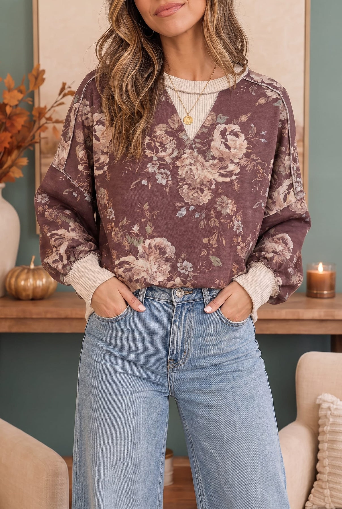 Styled front view of a mauve floral crewneck sweatshirt with cream ribbed trim and light-wash jeans
