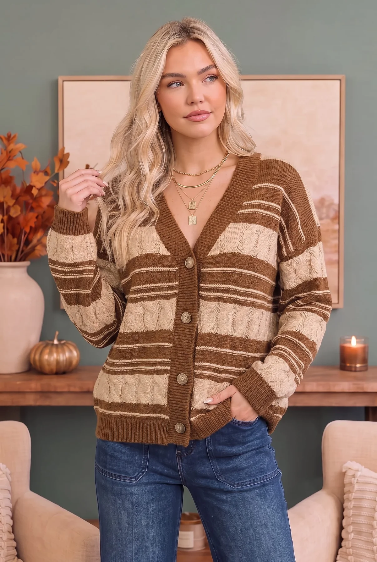 Front view of a woman wearing a brown and cream striped cable-knit button cardigan with blue jeans