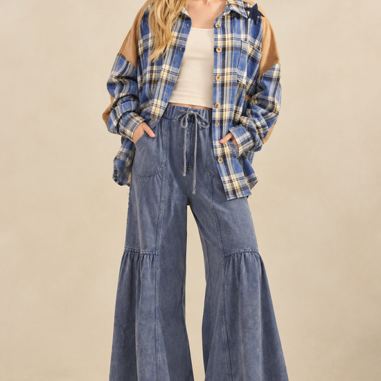 Star patch plaid flannel styled with blue tiered wide-leg drawstring pants, a cream tank, and cream sneakers.
