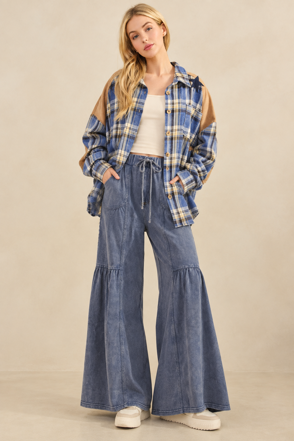 Star patch plaid flannel styled with blue tiered wide-leg drawstring pants, a cream tank, and cream sneakers.